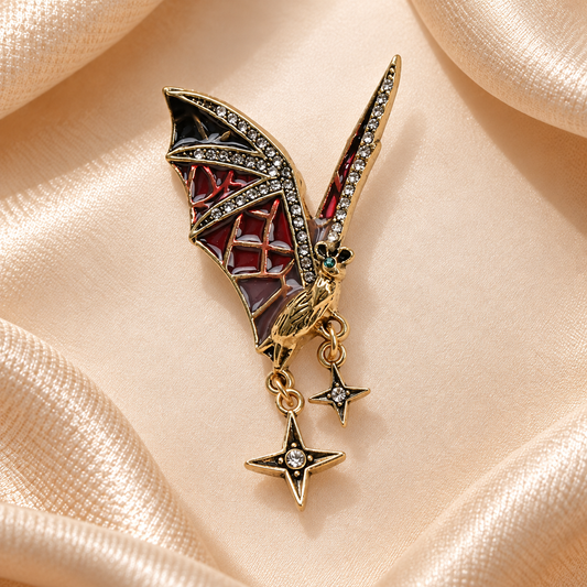 Broche chauve-souris gothique dorée à ailes rouges et noires et pendentifs étoiles sur fond carré en satin champagne