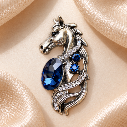 Broche tête de cheval argentée avec pierres bleu saphir et strass sur fond satin champagne-beige