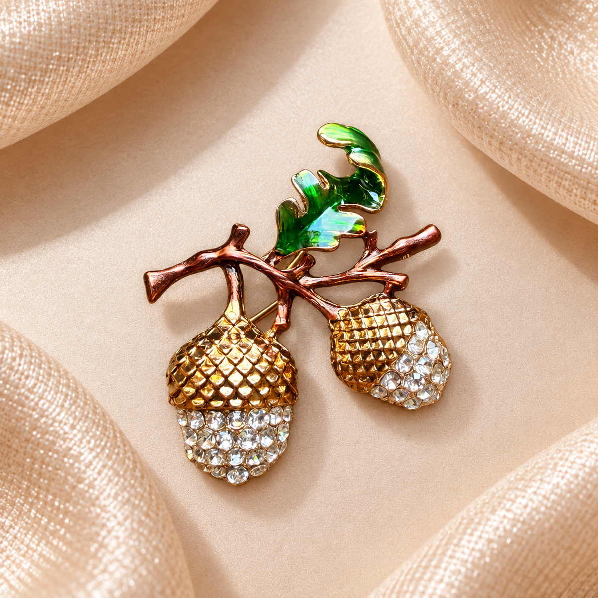 Broche deux glands dorés ornés de strass avec feuille verte sur fond satin champagne-beige