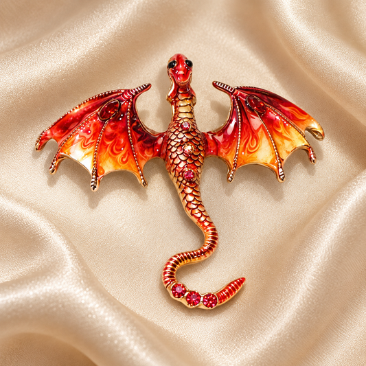 Broche dragon rouge et orange aux ailes déployées sur fond satin champagne