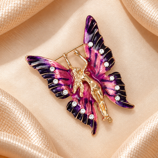 Broche fée papillon violet et rose avec strass et monture dorée sur fond carré de satin champagne