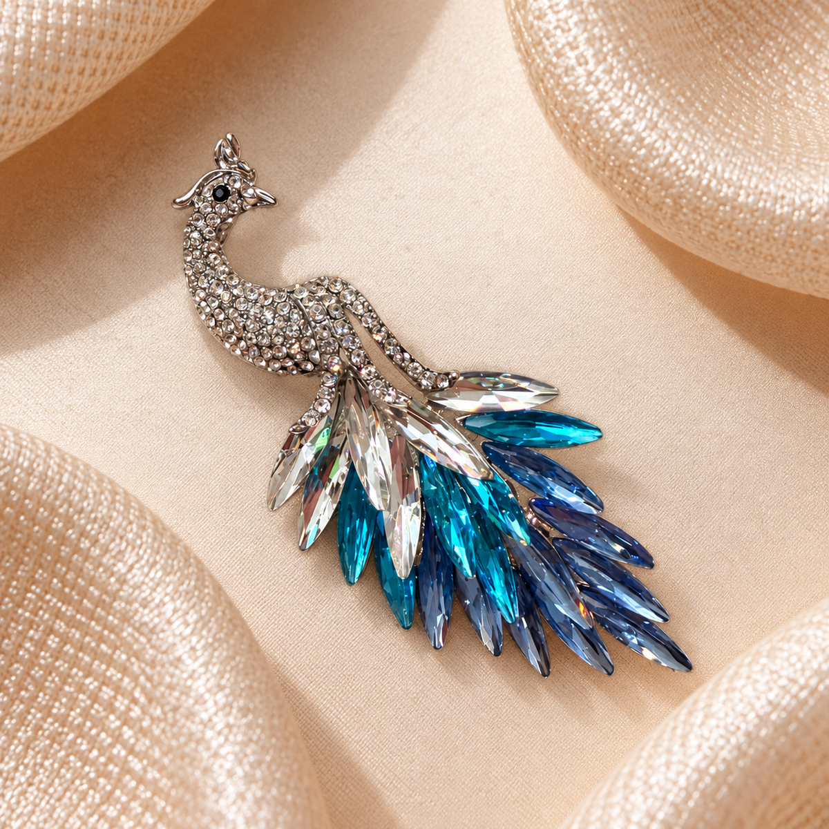 Broche paon argenté à strass et plumes bleu turquoise sur tissu champagne satiné, visuel carré
