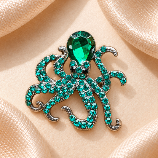 Broche pieuvre aux strass turquoise et pierre vert émeraude sur fond satin champagne-beige